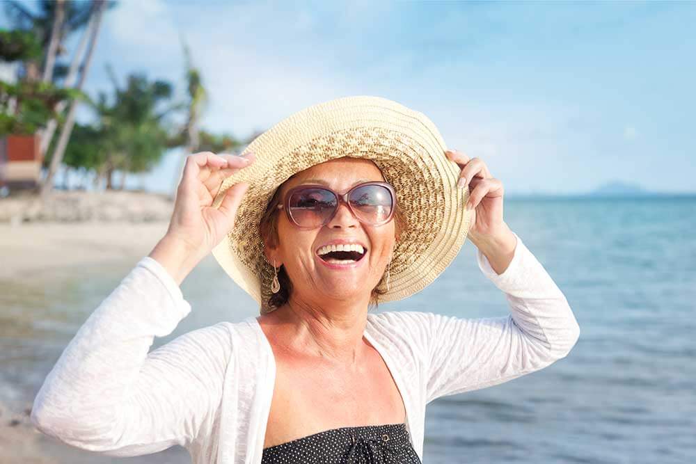 Happy woman in a hat at the beach